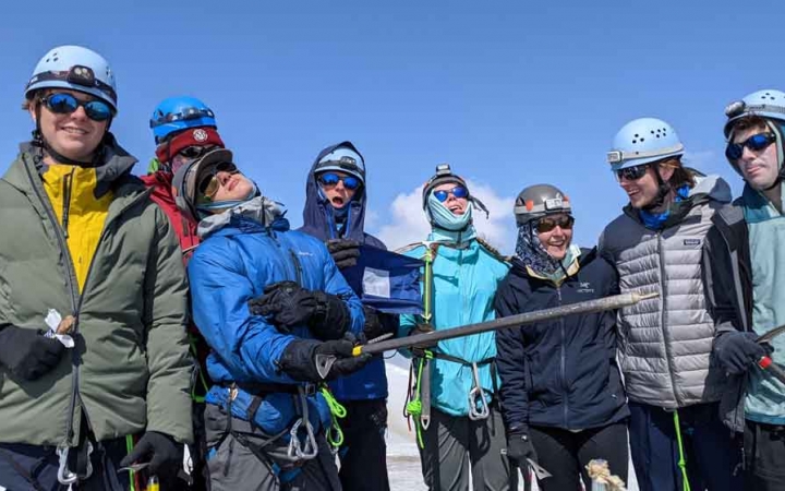 a group of people wearing mountaineering gear pose for a photo on an outward bound course